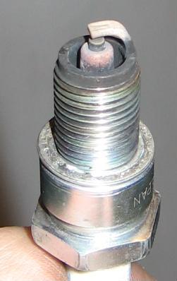 1990 Nissan Micra - A close-up view of a single spark plug, showing its threaded base and electrode tip.