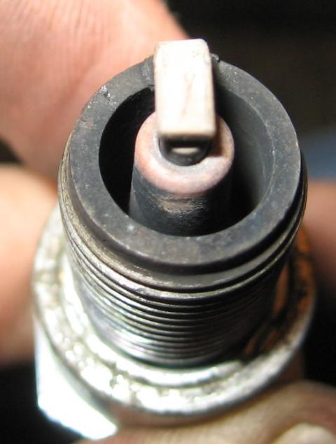 1990 Nissan Micra - Close-up view of a spark plug, showing wear on the electrode and insulator.