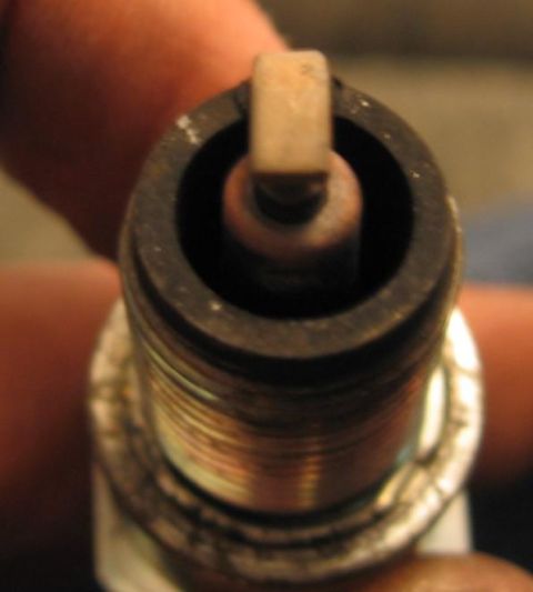 1990 Nissan Micra - A close-up view of a single spark plug, showing its electrode and threaded base.