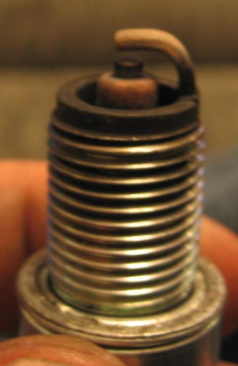 1990 Nissan Micra - A close-up view of a used spark plug shows significant carbon buildup.