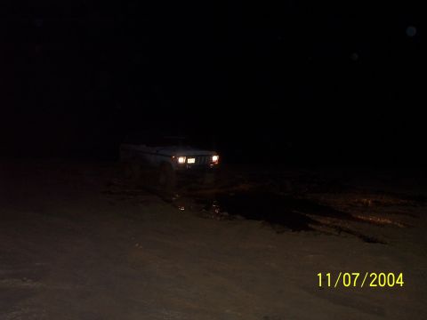 1979 Ford Bronco - Ford Bronco navigates muddy terrain under headlights at night.
