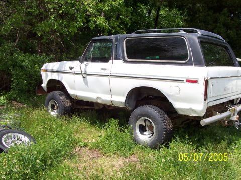 1979 Ford Bronco - A white 1978 Ford Bronco with a black top sits in a grassy area, showing its lifted suspension and off-road tires.