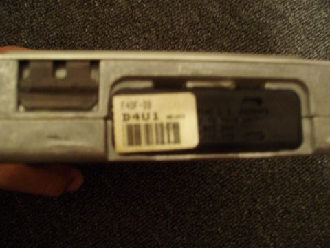 1993 Ford Taurus - A label with a barcode and part number is affixed to a metallic automotive component.