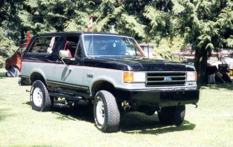 1989 Ford Bronco - A two-tone black-over-silver 1989 Ford Bronco full-size SUV shown from the front-three-quarter angle, with removable hardtop, lift kit, whi…