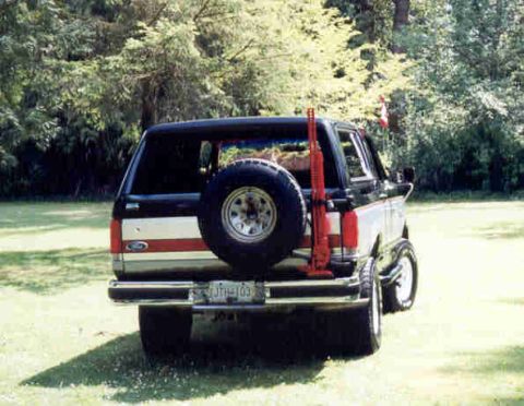 1989 Ford Bronco - The rear of a Ford Bronco is shown with a spare tire and a gun rack attached.