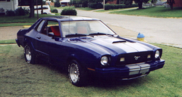 1977 Ford Mustang II coupe, blue with white racing stripes, parked on grass