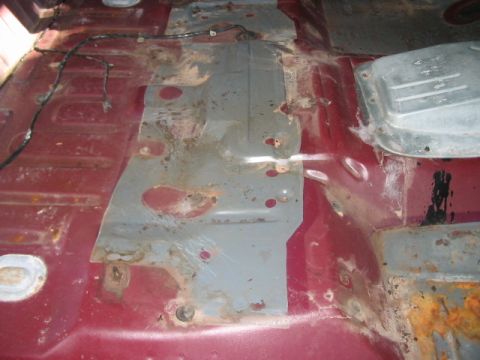 1991 Ford Bronco - The interior floor of a vehicle shows significant rust and repair patches.