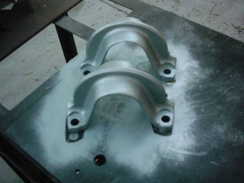 1978 Ford Bronco - Two silver bearing caps are shown on a surface with white overspray, likely during a painting process.