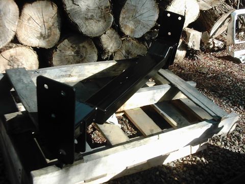 1978 Ford Bronco - A black metal bracket sits on a wooden pallet, with a stack of logs behind it. The Supermotors.net logo is in the corner.