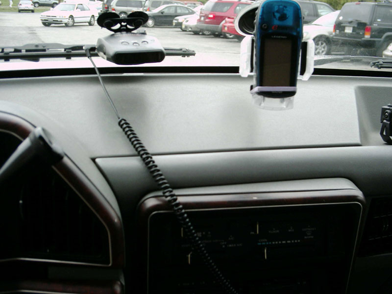 Dashboard interior with a blue GPS device and a radar detector mounted on the windshield
