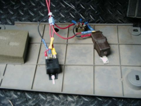 1988 Ford Bronco - Finished relay wiring laid out on a gray plastic interior trim panel over a diamond-plate surface: a black cube relay and a brown relay wir…