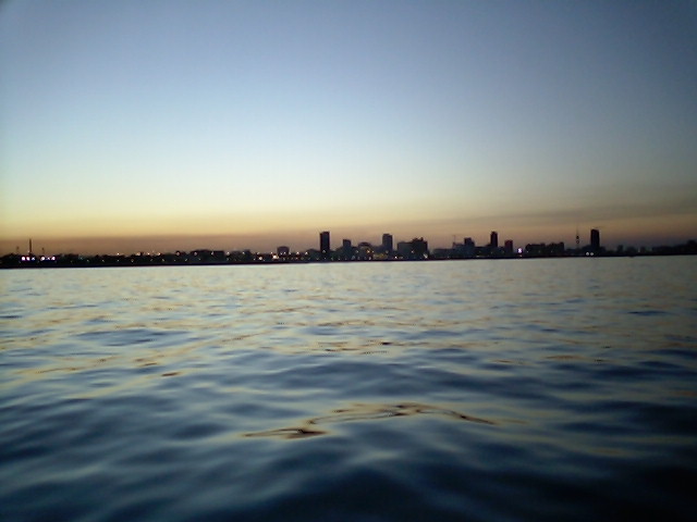 City skyline on the horizon over rippling water during sunset
