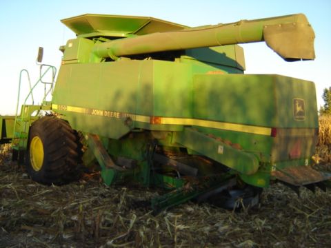 1992 Ford Bronco - A green John Deere combine harvester is seen from the side, parked in a field with harvested corn stubble.