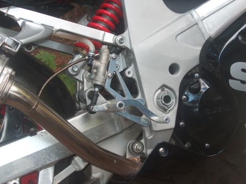 2002 Suzuki TL1000R - Close-up view of a motorcycle's rear brake system and exhaust pipe, with "SUZUKI" branding visible on the fairing.