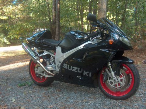 2002 Suzuki TL1000R - A black 2002 Suzuki TL1000R motorcycle with red wheels is parked outdoors on a gravel surface.
