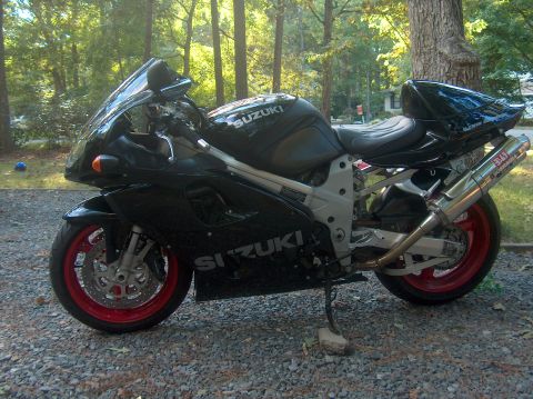 2002 Suzuki TL1000R - A black 2002 Suzuki TL1000R motorcycle is parked outdoors on a gravel surface, red-painted rims.