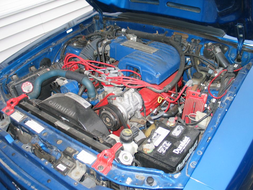 Blue 1990 Ford Mustang engine bay with V8 engine, red spark plug wires, and blue intake manifold