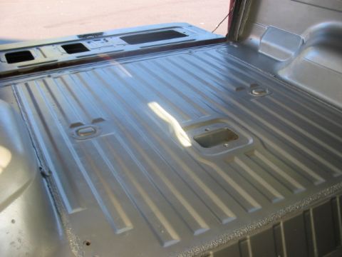 1991 Ford Bronco - The ribbed interior of a truck bed shows tie-down points and a fifth-wheel hitch receiver.