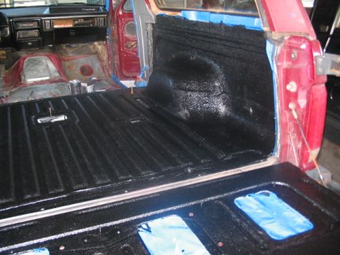 1991 Ford Bronco - The interior of a vehicle is being worked on, with black spray-on bed liner applied to the cargo area.