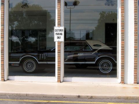 2000 Ford Crown Victoria - Lincoln Mark V coupe seen through a storefront window, hood is open.