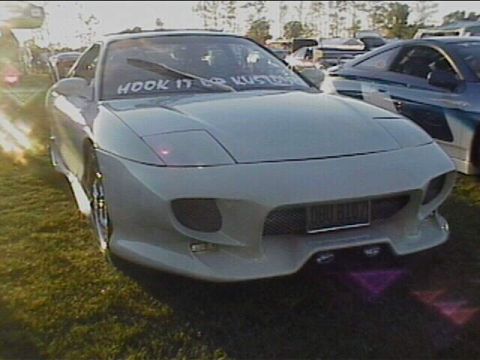 1994 Ford Probe - A white sports coupe is parked on grass with a custom banner on its windshield and a license plate that reads 'DBU 8107'.