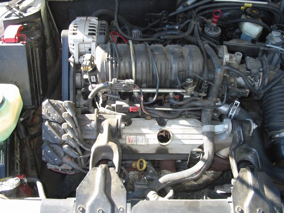 Engine bay view of a transverse V6 with intake manifold, alternator, and battery