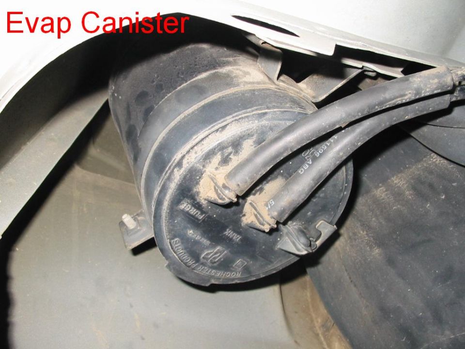 Black EVAP charcoal canister mounted in wheel well with vapor hoses attached
