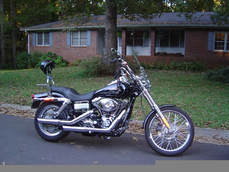Black Harley-Davidson cruiser motorcycle parked side-on in front of a brick house