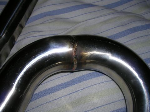 1996 Ford Probe - Shiny metal exhaust pipe section with a visible weld, resting on a striped fabric surface.