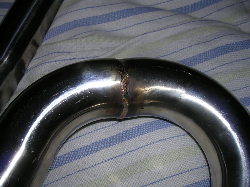 Close-up of a shiny metal exhaust pipe section showing a welded joint