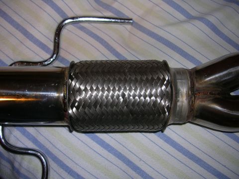1996 Ford Probe - Close-up of a vehicle exhaust flex pipe with braided metal construction and a chrome bracket.