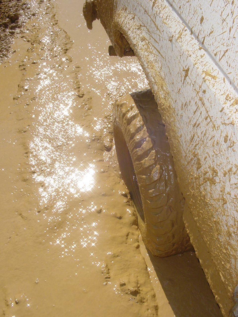 Muddy tire of a vehicle stuck in a mud puddle