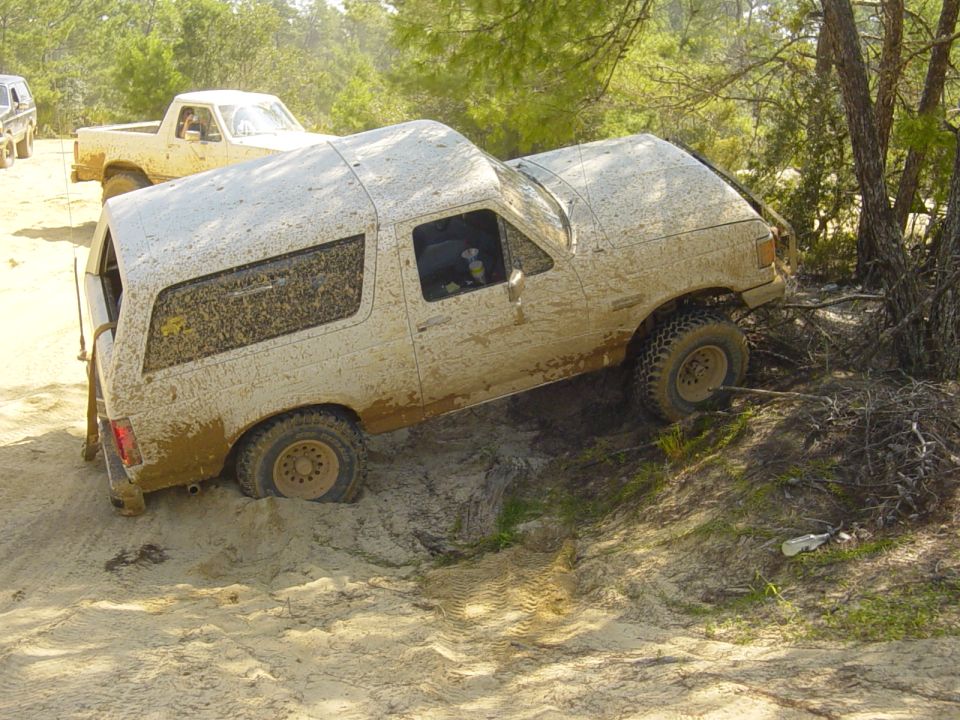 Muddy SUV stuck on a dirt hill with another truck behind it