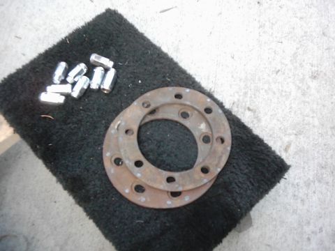 1978 Ford Bronco - Two rusty brake rotors and a set of lug nuts are laid out on a black mat.