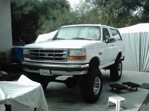 1978 Ford Bronco - This lifted white Ford Bronco is shown from the front 3/4 angle, with a California license plate visible.