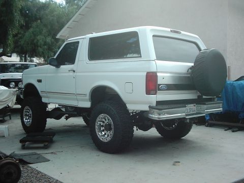 1978 Ford Bronco - Modified white Ford Bronco with lifted suspension and spare tire on the rear.