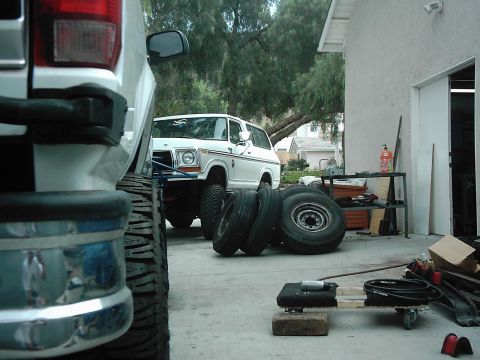 1978 Ford Bronco - A white 1978 Ford Bronco is parked in a driveway with spare tires stacked in front of it.