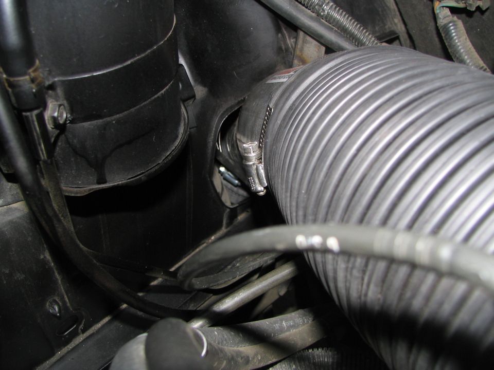Corrugated intake hose and black plastic housing in an engine bay