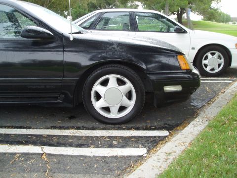 1993 Ford Taurus - A black 1993 Ford Taurus SHO is parked next to a white car in a parking lot.