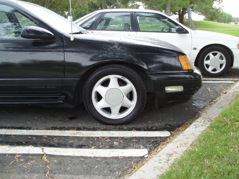 Black 1993 Ford Taurus SHO parked next to a white car, front quarter view