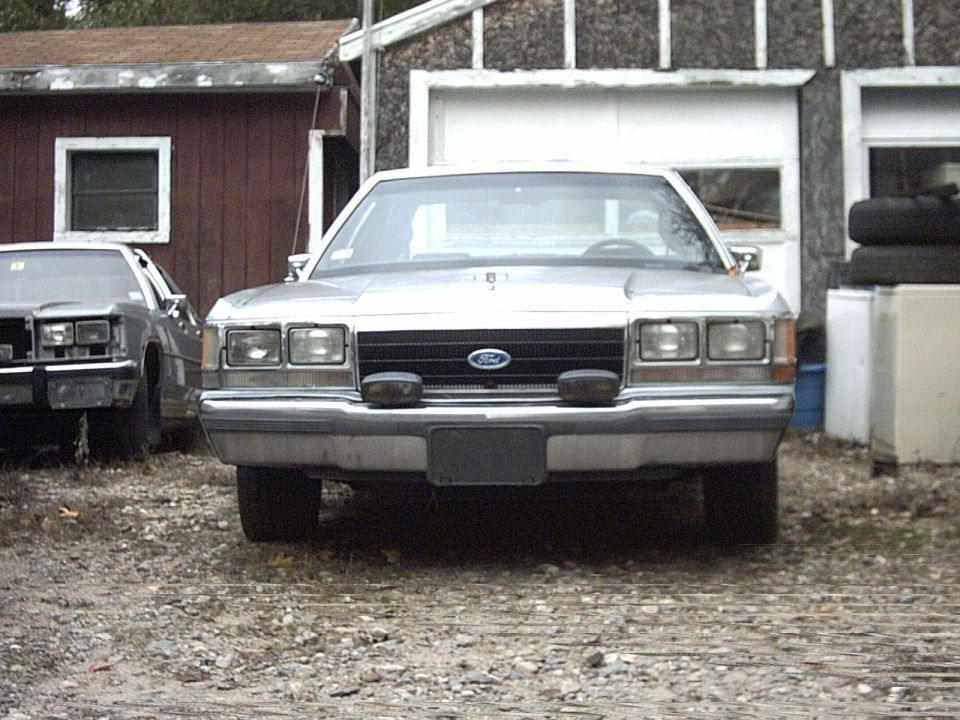 1991 Ford Crown Victoria LTD parked in front of a garage, another car to the left