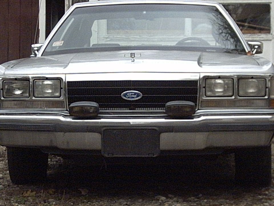 Front view of a silver Ford Crown Victoria with a black grille and two fog lights