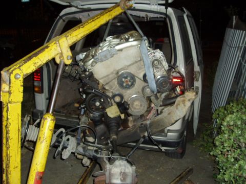 1993 Ford Taurus - An engine is being removed from the back of a van using an engine hoist.