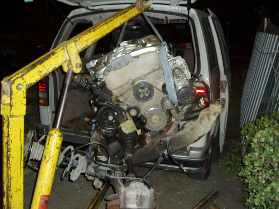 engine being lifted out of a van with a yellow engine hoist