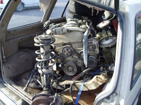 1993 Ford Taurus - Engine and suspension components are packed inside the cabin of a vehicle, obscuring the interior.