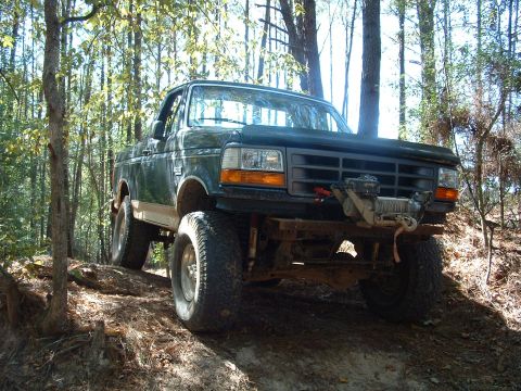 1993 Ford Bronco - A lifted Ford truck with a winch is shown off-road, appearing to be from the early to mid-1990s.