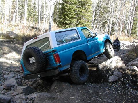 1994 Ford Bronco - 1994 Ford Bronco navigating a challenging rocky trail with an ATV following behind.