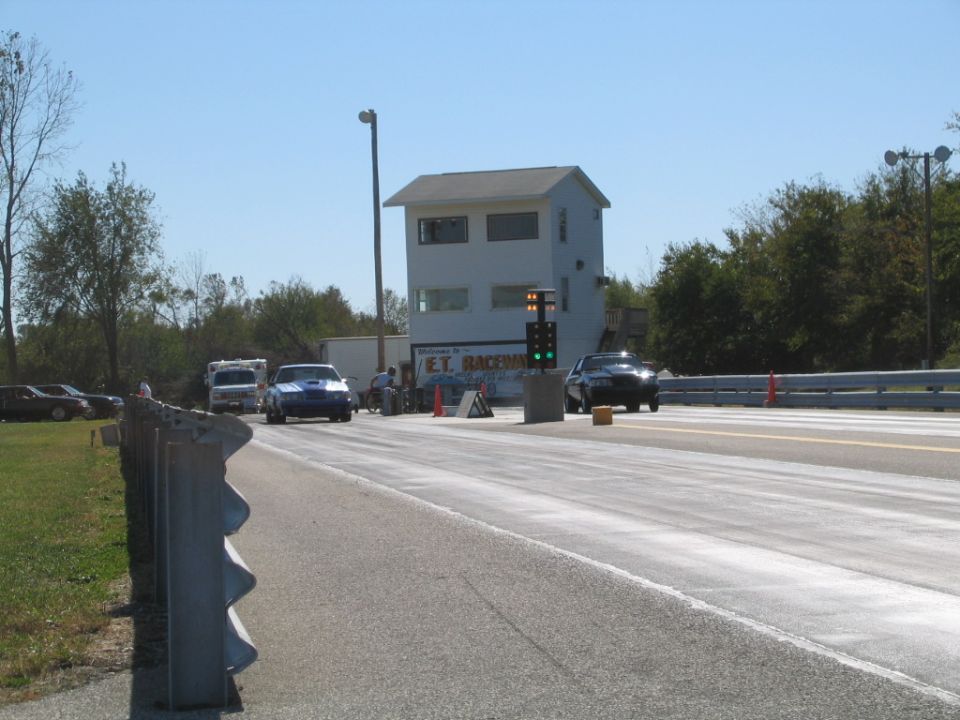 Drag strip with 'E.T. Raceway' timing tower and two cars staged at the line
