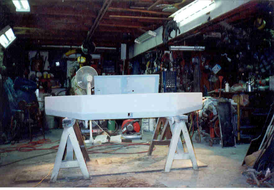 White-primered front bumper on sawhorses in a cluttered garage workshop