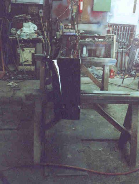 1989 Ford Bronco - A dark panel rests on sawhorses in a cluttered garage or workshop environment.